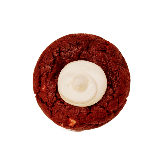 Picture of a red vanilla cookie stuffed with white chocolate chunks and a center topping of cream cheese